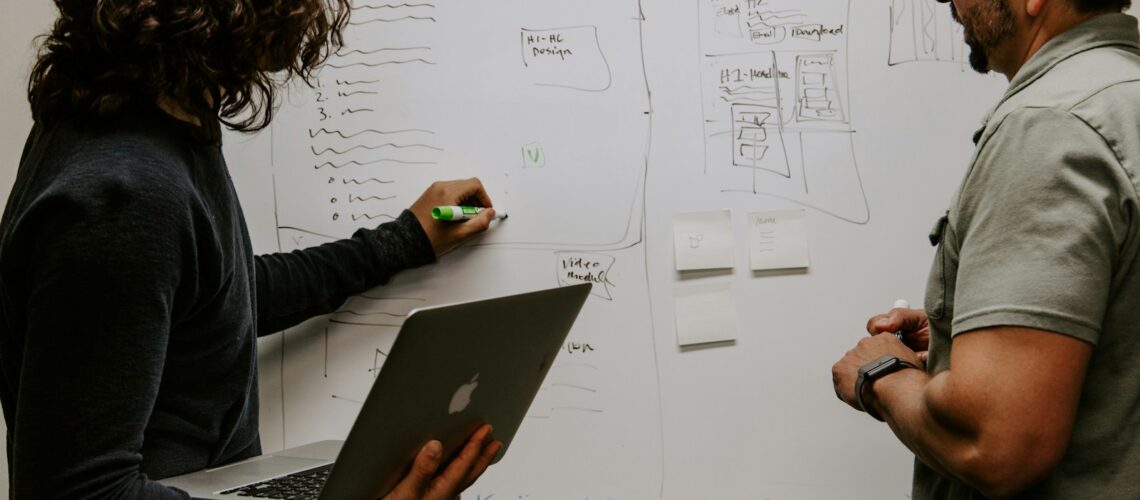 man wearing gray polo shirt beside dry-erase board