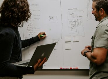 man wearing gray polo shirt beside dry-erase board