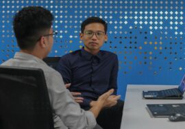 two men sitting at a table talking to each other