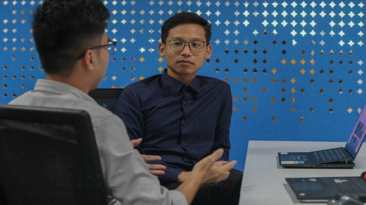 two men sitting at a table talking to each other