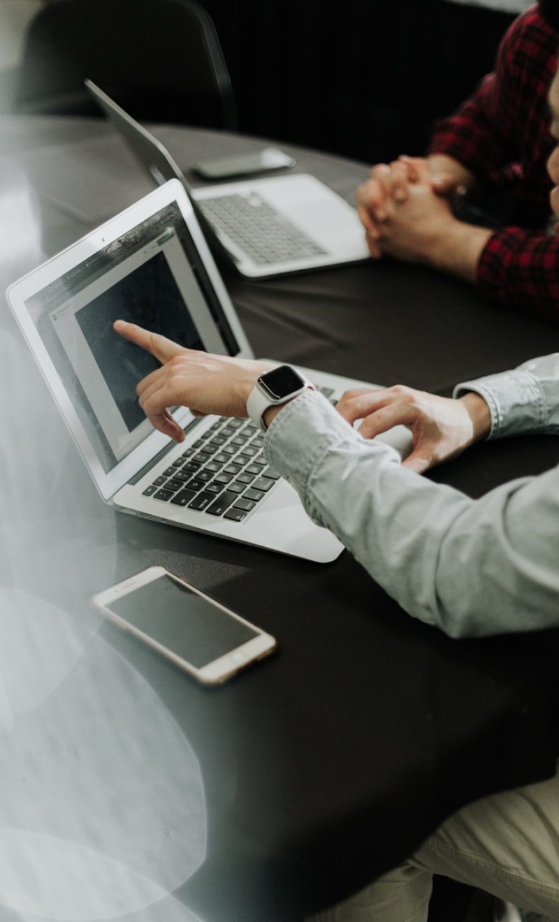 two people sitting at a table with laptops