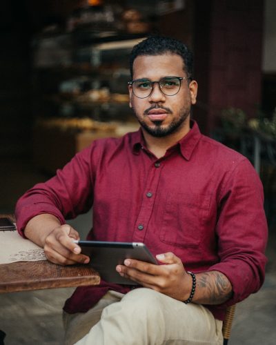 man in red dress shirt holding black tablet computer